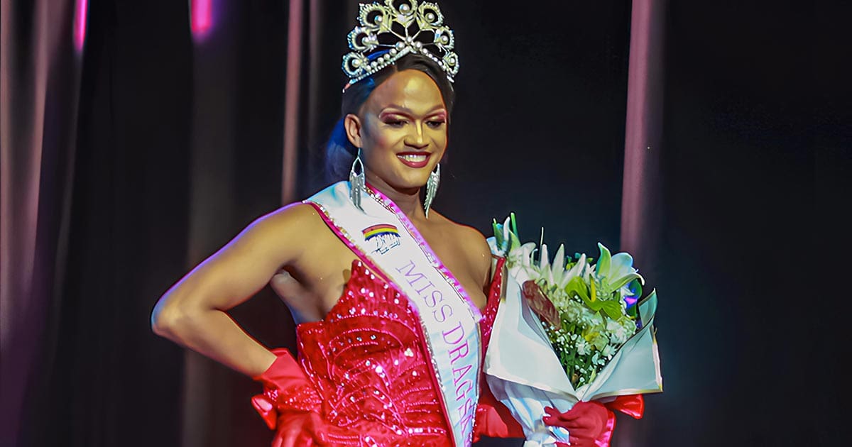 An on-stage photo of Anastasia K-Boney, the winner of Miss Drag South Africa 2024, holding a bouquet of flowers